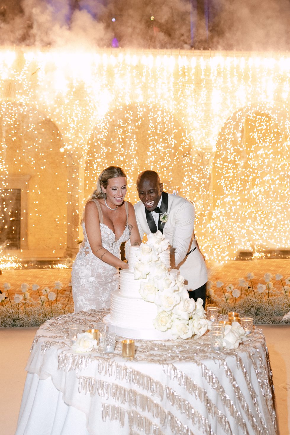 Beatrice and Evan cutting the cake under a curtain of lights at Castello di Bracciano, near Rome