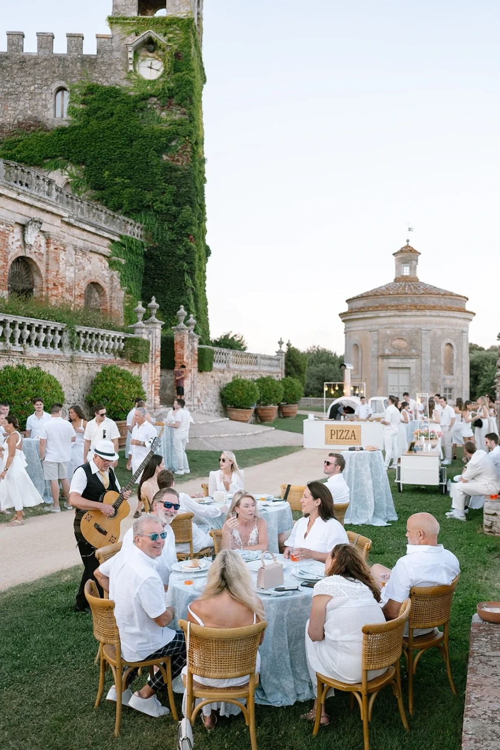 Guests at long tables in the gardens of Castello di Celsa