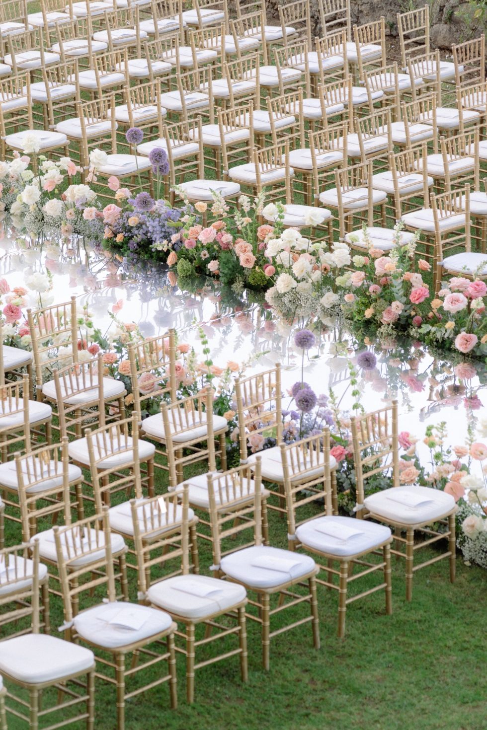 Gold chairs and pastel flowers along the ceremony aisle at Castello Odescalchi di Bracciano