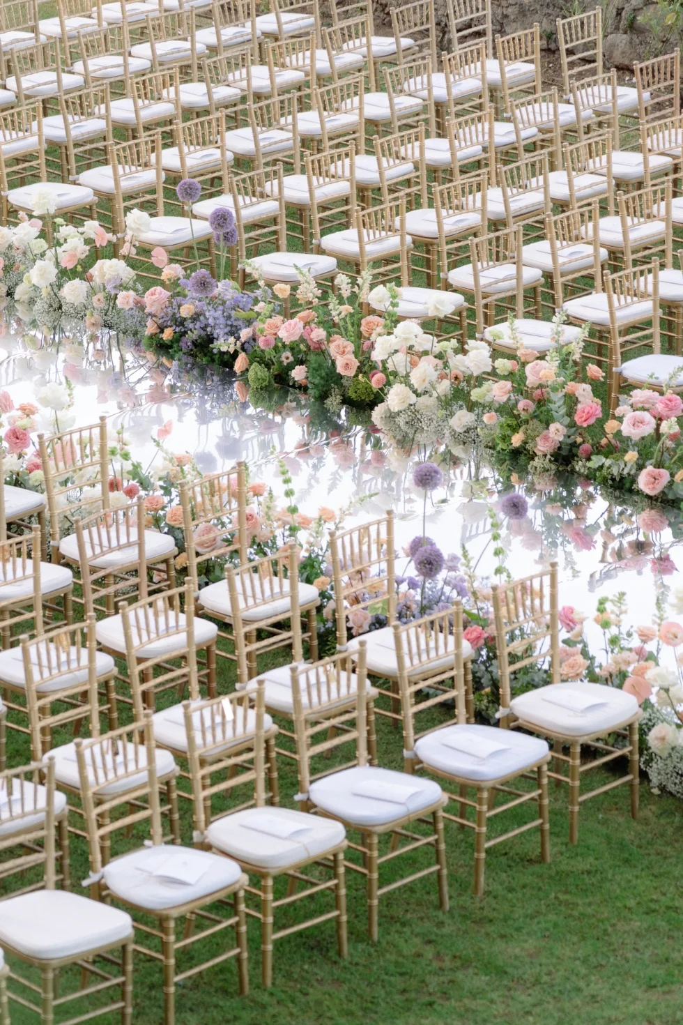 Gold chairs and pastel flowers along the ceremony aisle at Castello Odescalchi di Bracciano