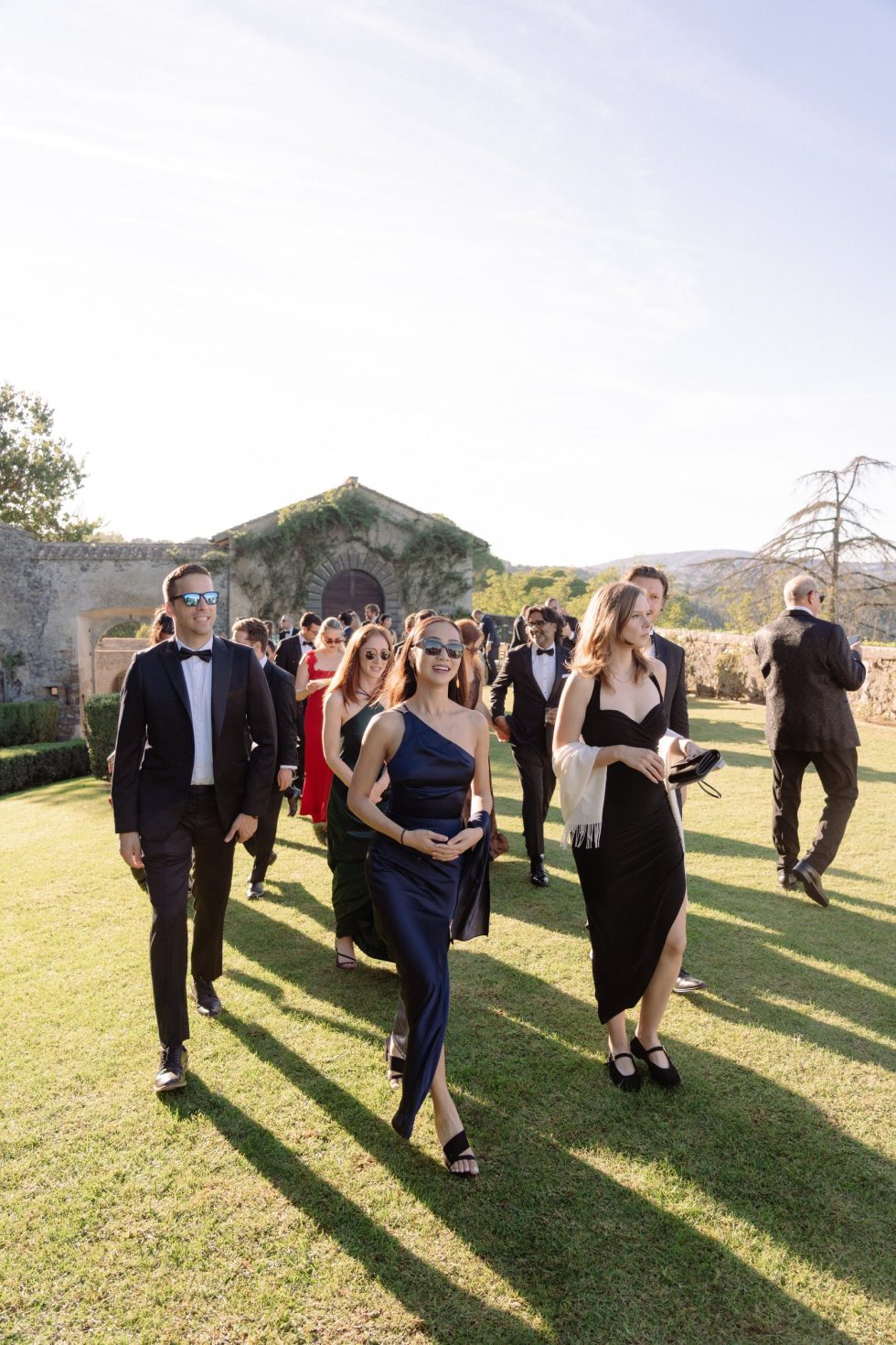 Wedding guests walking across the lawn of Castello Odescalchi in the golden light