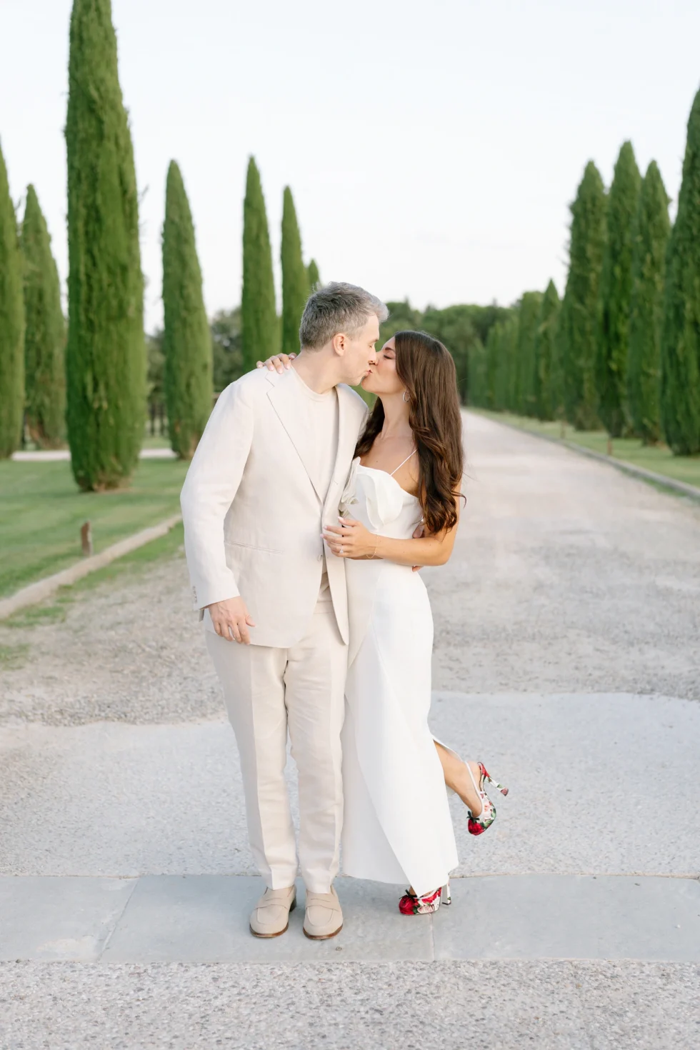 Il Borro wedding photographer: Remy and Toby kissing on the cypress avenue of the estate at their pizza party, Tuscany