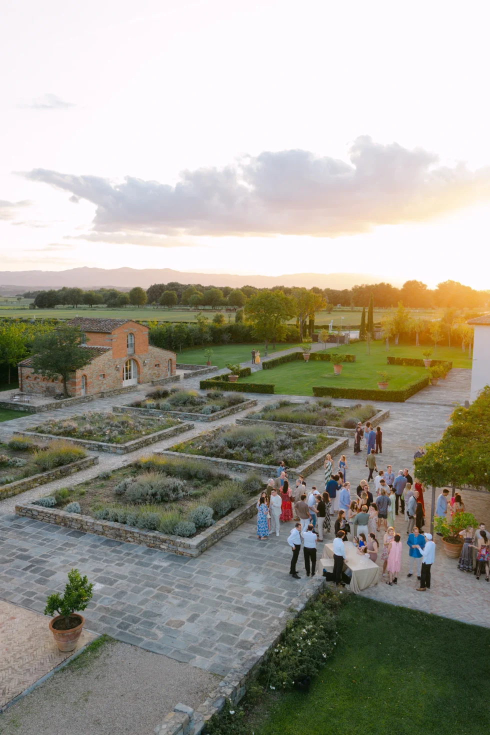 Guests gathering in the Italian garden of Il Borro at sunset for the pizza party