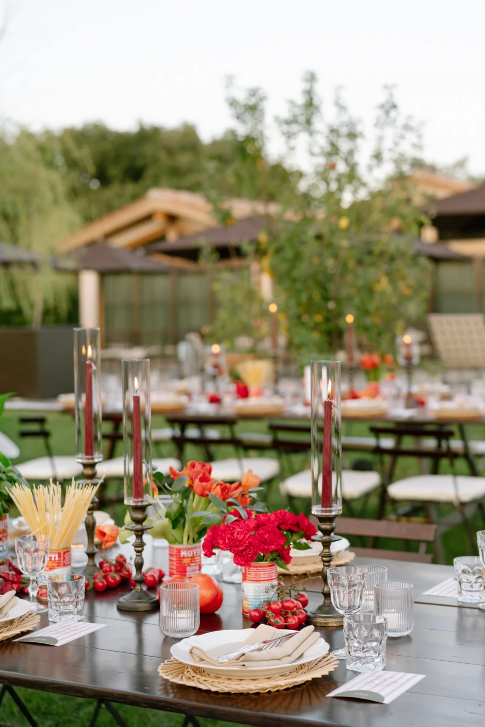 Welcome dinner ideas for a wedding in Italy: long tables with red flowers, candles and tomatoes at Il Borro