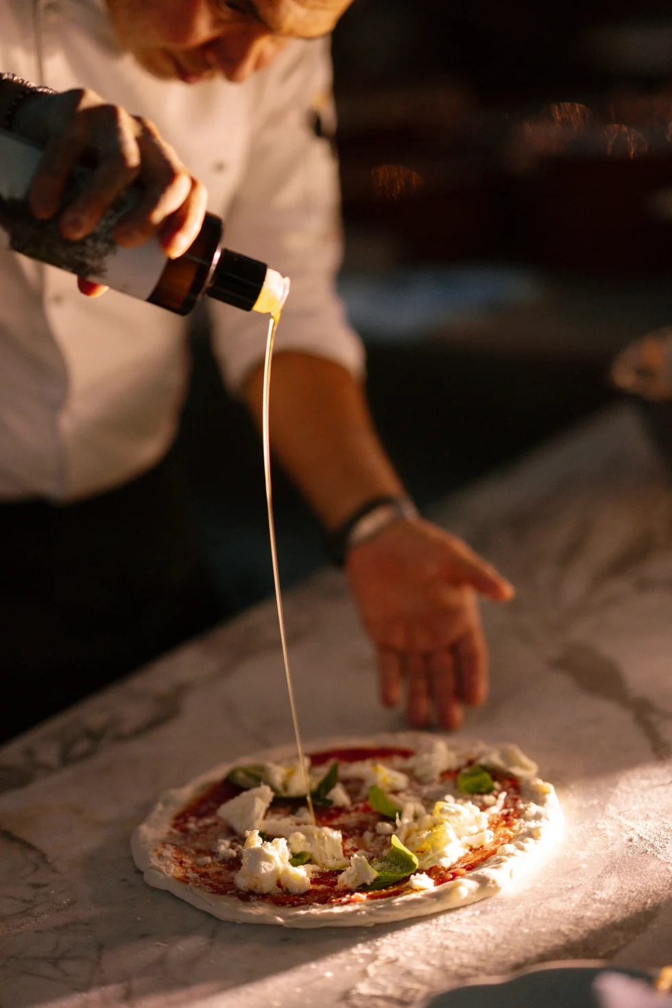 Olive oil poured over a freshly baked pizza at the welcome party at Il Borro