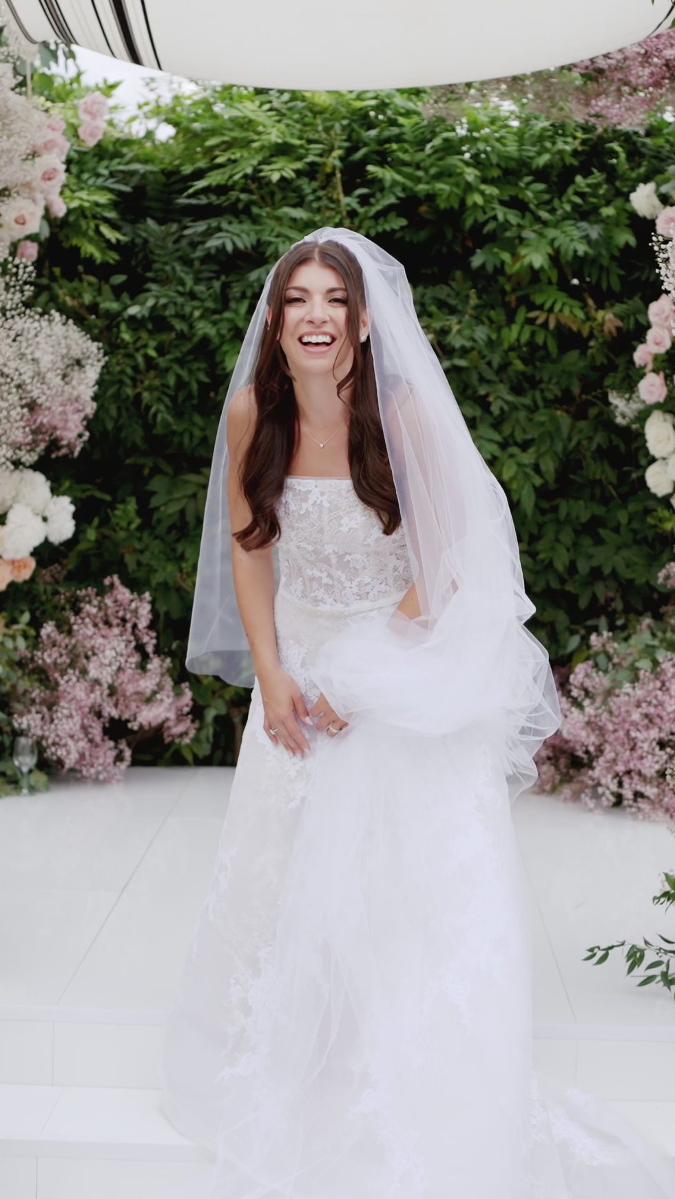 The bride laughing beneath her veil at the floral ceremony, Il Borro