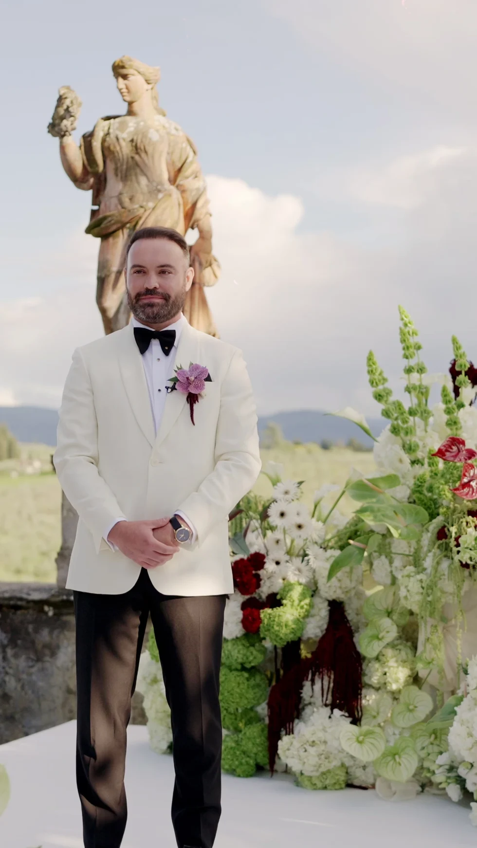 Jameson waiting at the floral ceremony altar among the statues of Villa Corsini