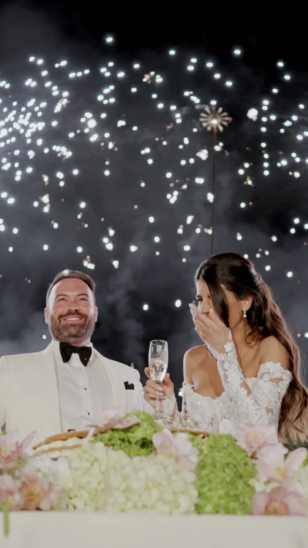 Jenna and Jameson laughing beneath falling sparks at their wedding dinner, Villa Corsini