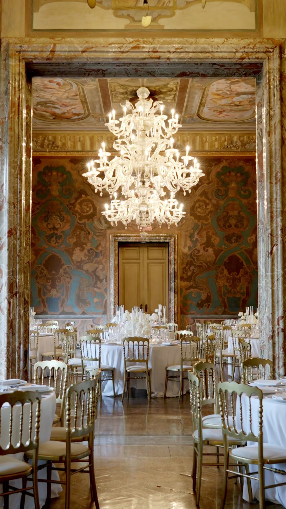 The wedding dinner set beneath a Murano chandelier at Villa Erba