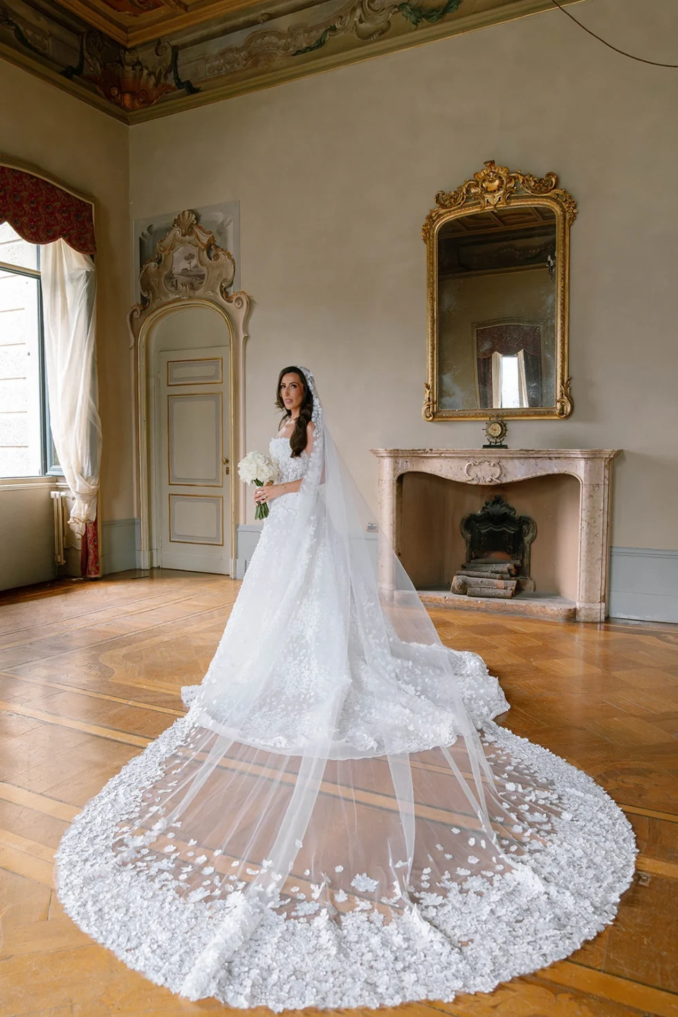 Renee with a long lace veil in a historic salon of Villa Erba before the ceremony
