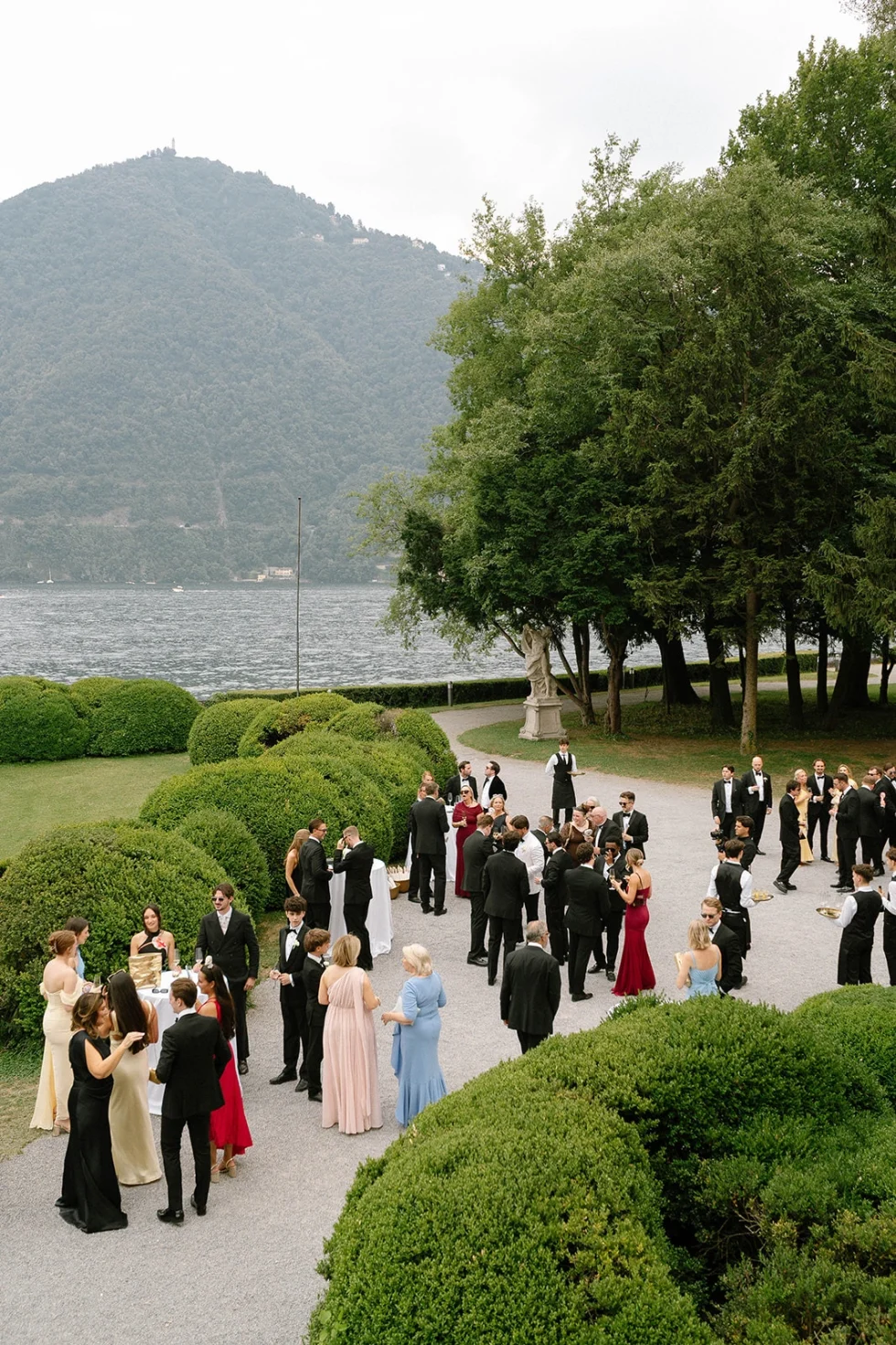 Wedding guests gathering in the gardens of Villa Erba with Lake Como behind