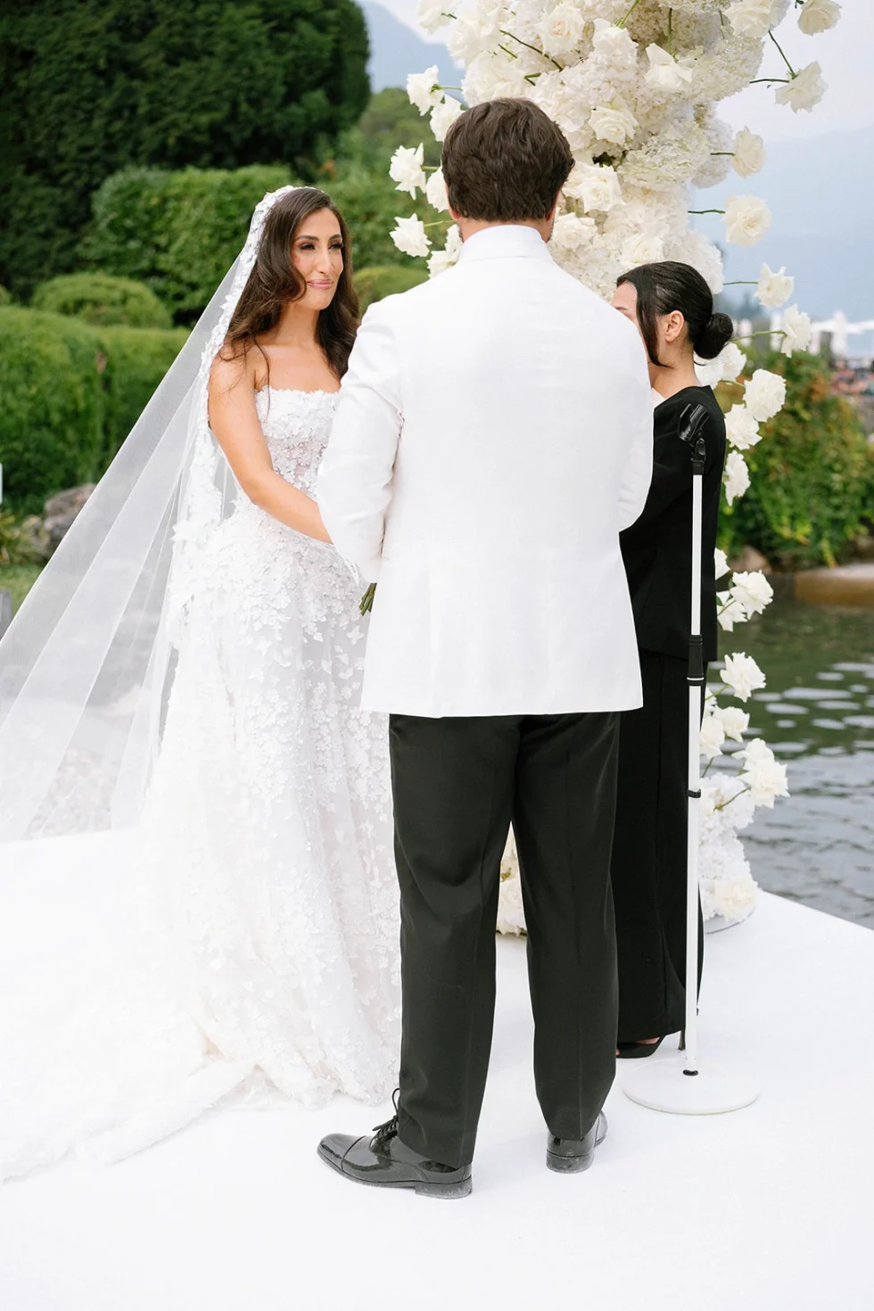 Wedding ceremony under a white floral arch on the lake at Villa Erba, Lake Como