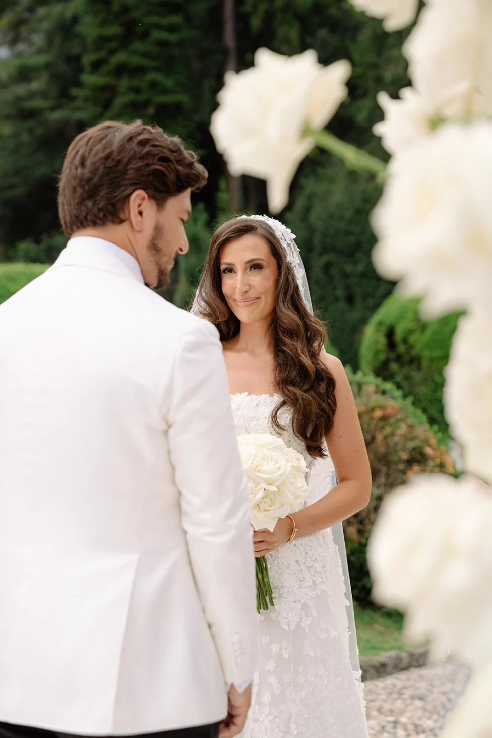 Groom seeing the bride among white flowers at Villa Erba, Lake Como wedding