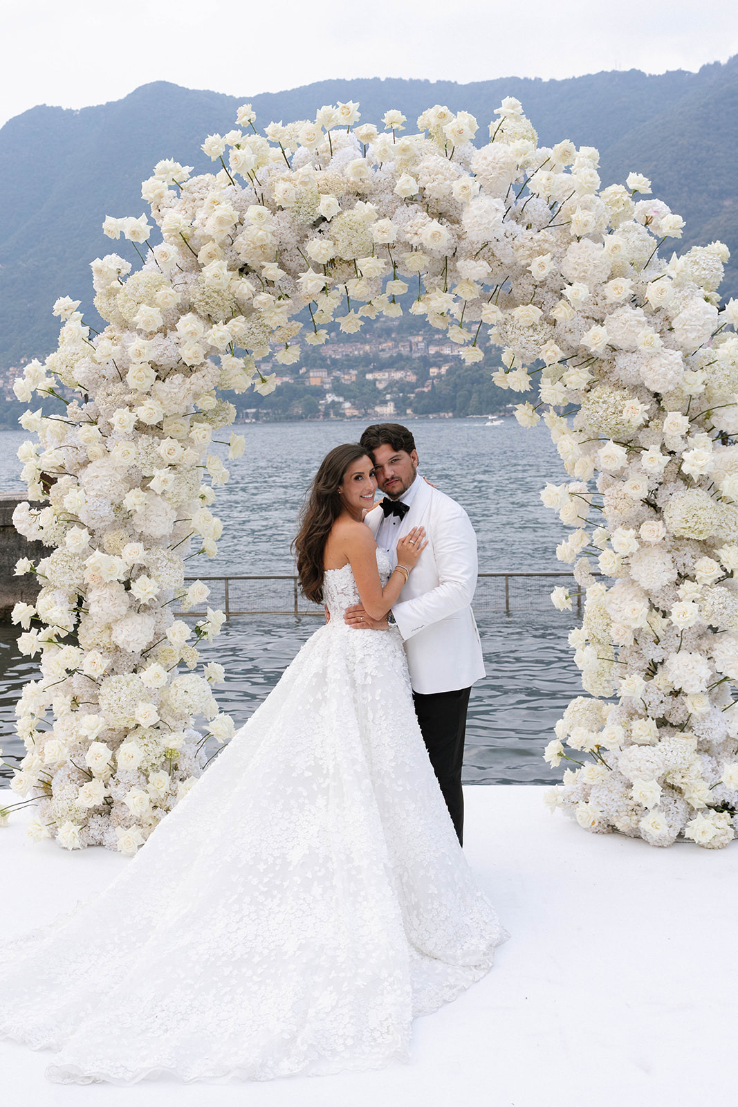 Villa Erba wedding photographer Lake Como Bride and groom under a white rose arch on Lake Como, Villa Erba wedding photographer
