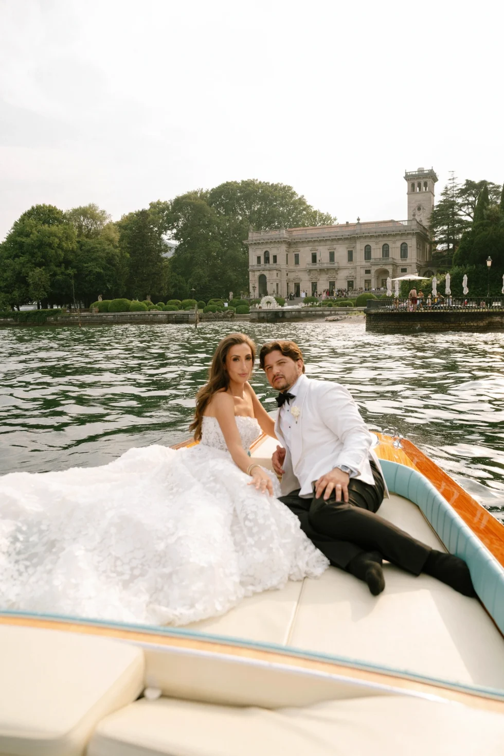 Lake Como wedding photographer: bride and groom relaxing on a Riva-style boat with Villa Erba behind