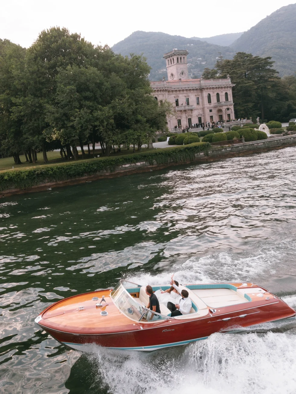 Lake Como wedding cost and venues: newlyweds on a classic wooden speedboat near Villa Erba