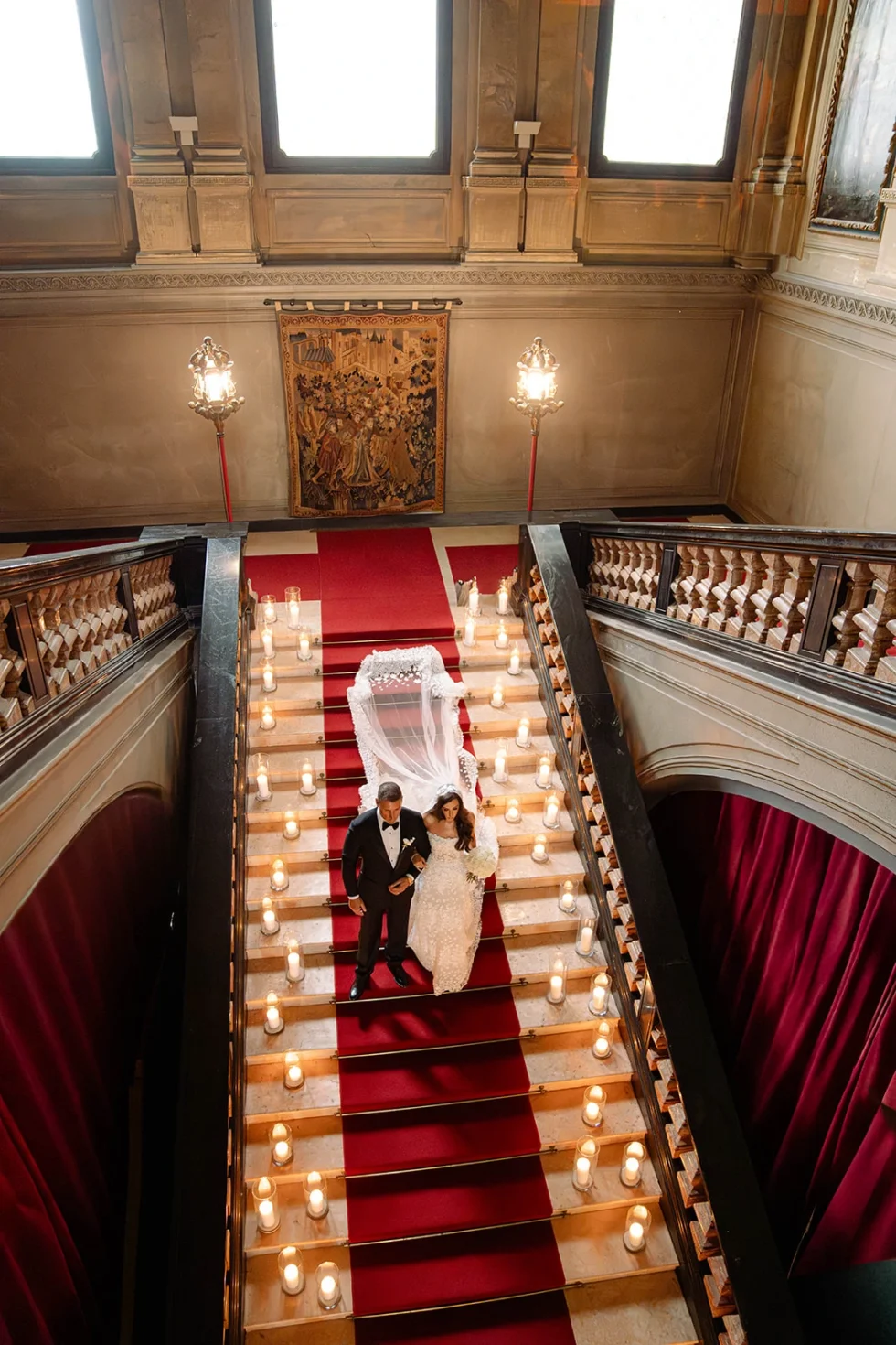 Renee and Tino descending the candlelit grand staircase of Villa Erba, seen from above, Lake Como