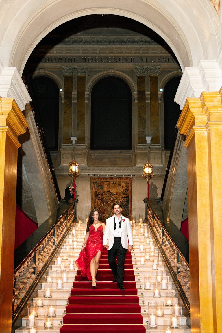 Bride in a red evening gown and groom on the candlelit staircase of Villa Erba