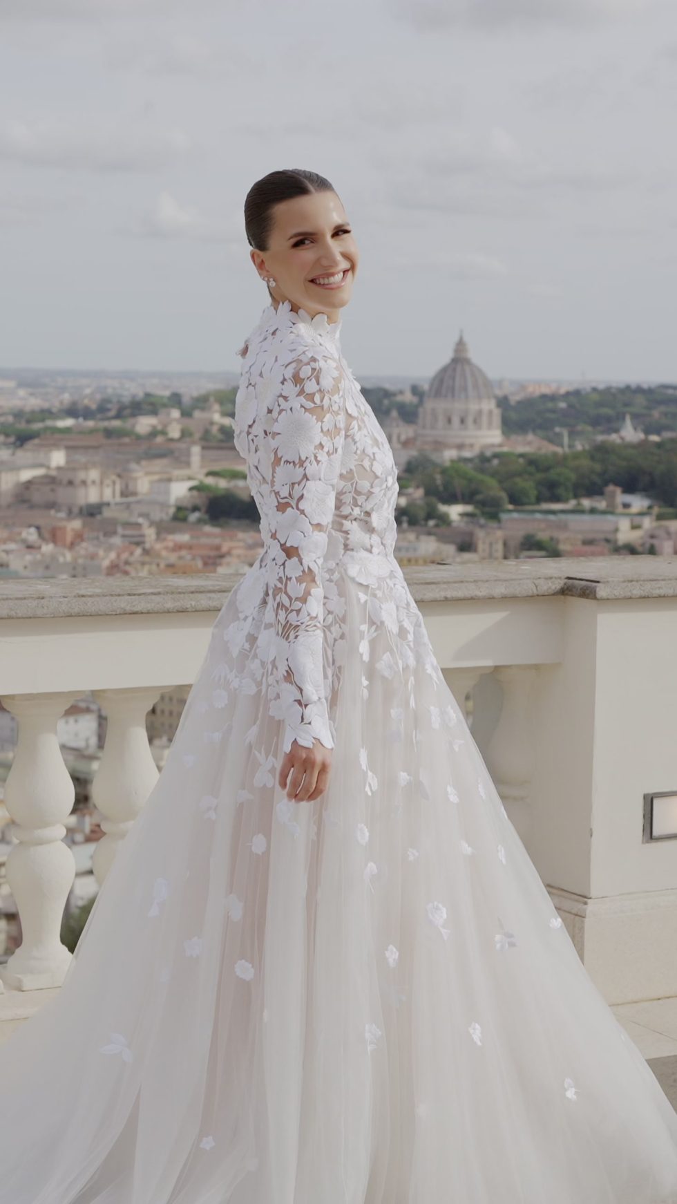 The bride in a floral lace gown on the terrace of Villa Miani, with the dome of St Peter's behind, Rome