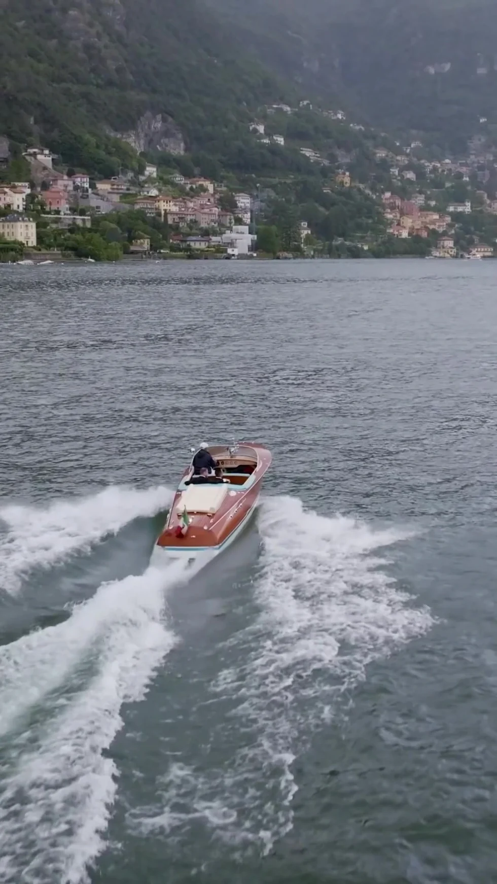 A classic wooden boat crossing Lake Como below Villa Pizzo