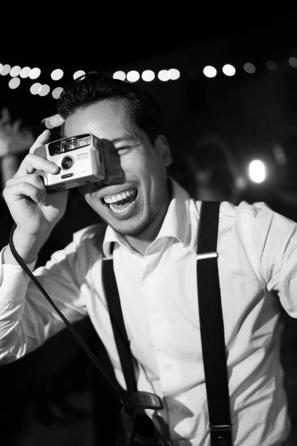 A guest with a vintage camera at the wedding party, black and white
