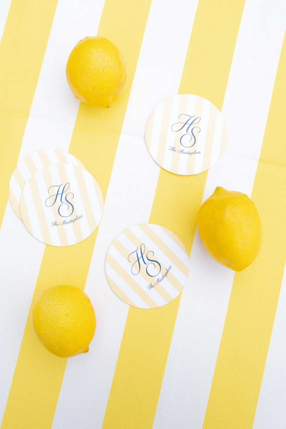 Monogrammed coasters for Hadi and Suzanne, The Mustaphas, among lemons on a yellow-striped tablecloth, Palazzo di Bagnaia